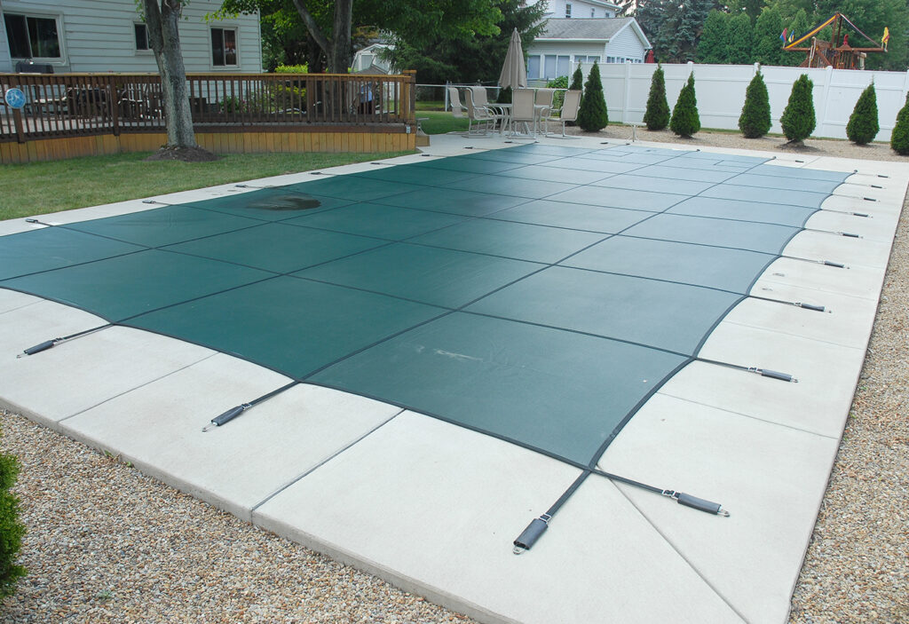 GLI OEM example of a green Secur-A-Pool cover anchored around a rectangular pool; example dimensions and step layout vary